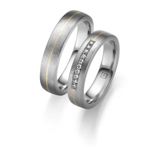 Auf dem Bild sieht man ein Trauringpaar aus 999 Tantal und mit einer 916er Gelbgold-Tauschierung. Der Damenring ist einzig allein mit Diamanten bestückt. Die Oberfläche beider Ringe ist sandmatt.
