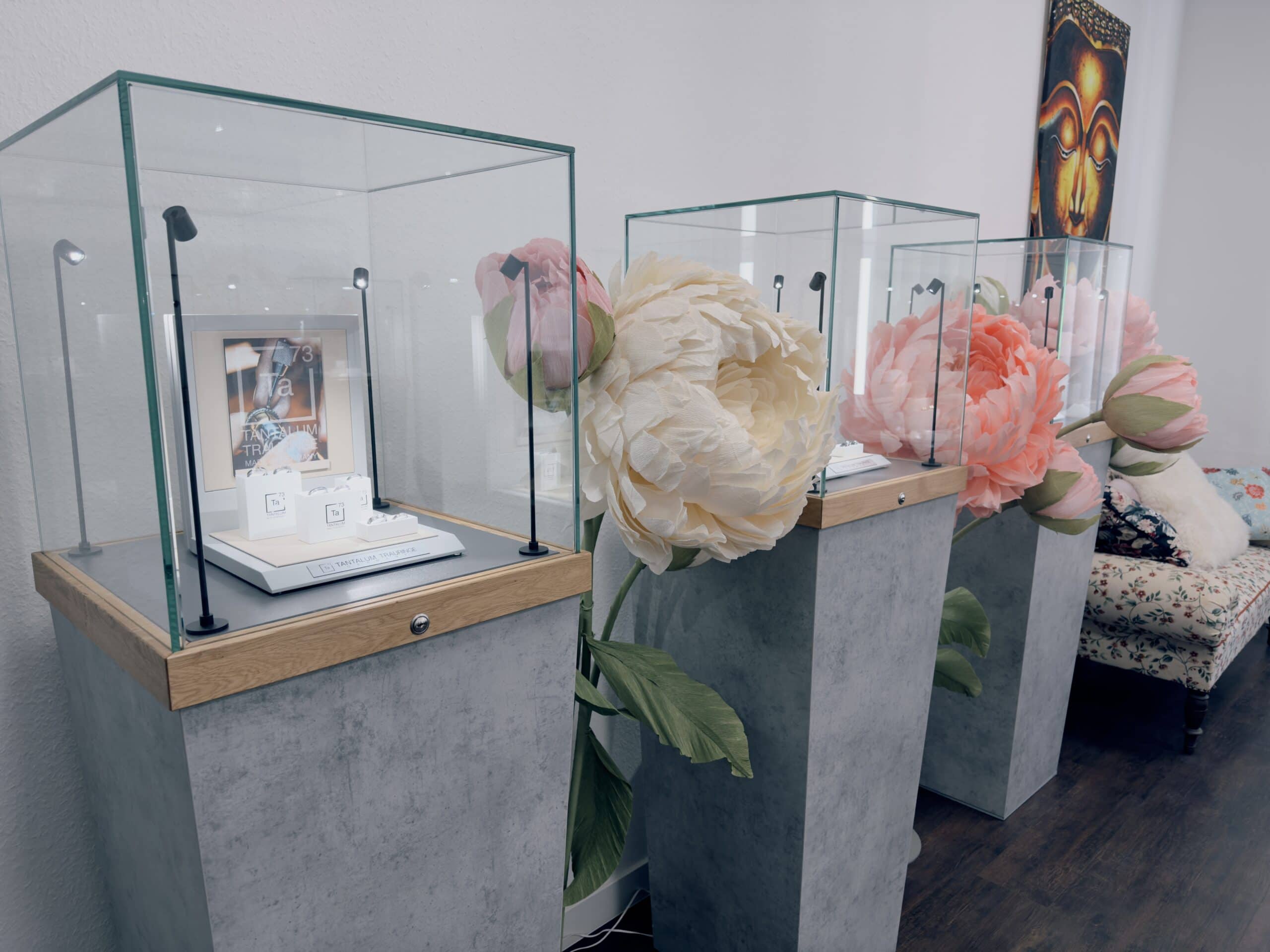 Displays-tantalum-trauringe Auf dem Bild sieht man graue Vitrinen und Blumen. Es sind die Aussteller der Marke Tantalum Trauringe.